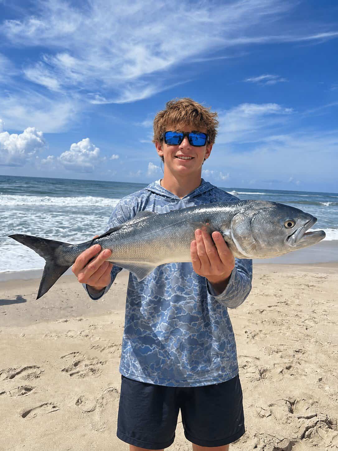 Angler holding a bluefish caught from the Outer Banks surf