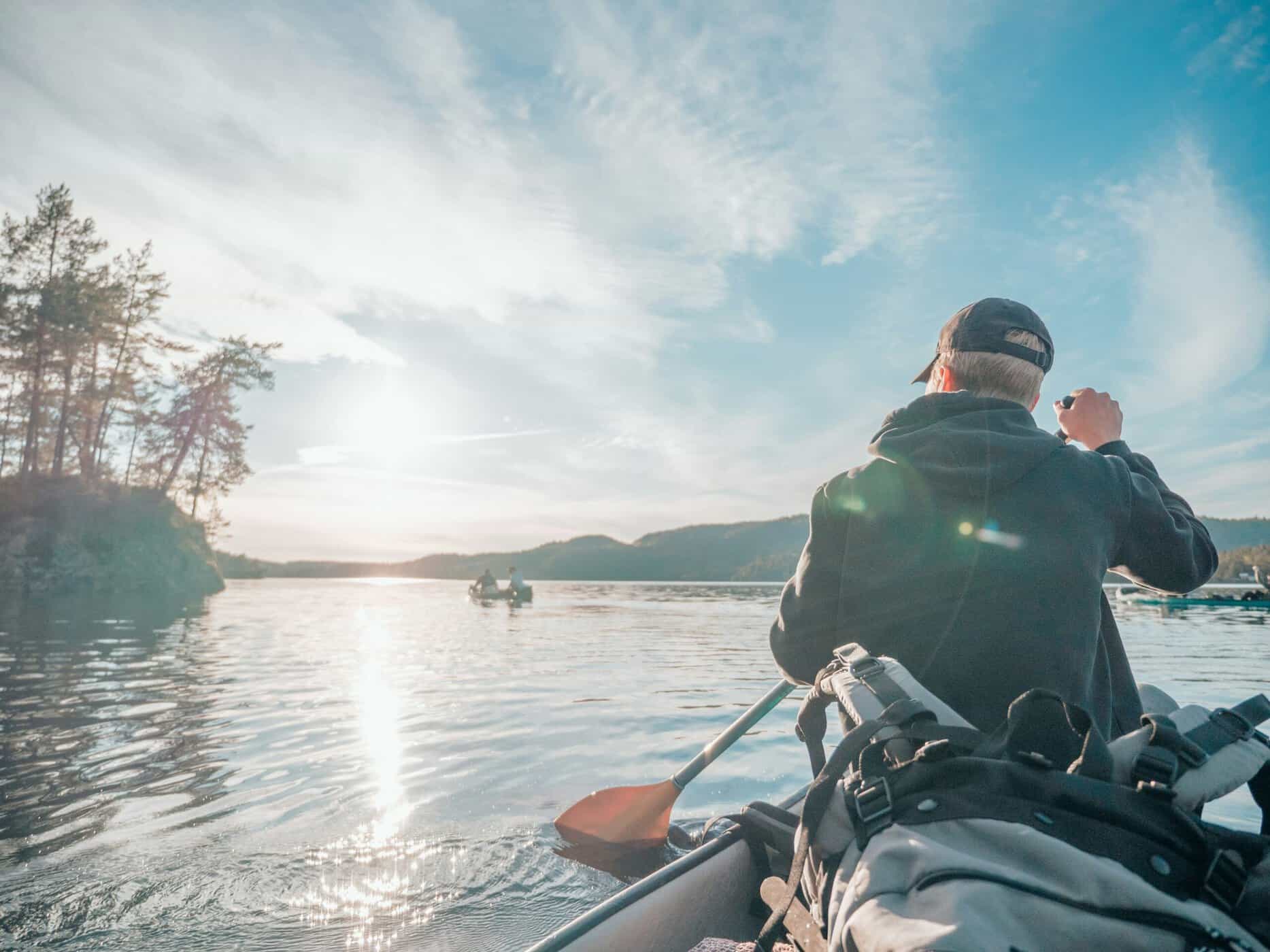 Angler paddling a kayak on calm protected water at sunrise with fishing gear rigged and ready