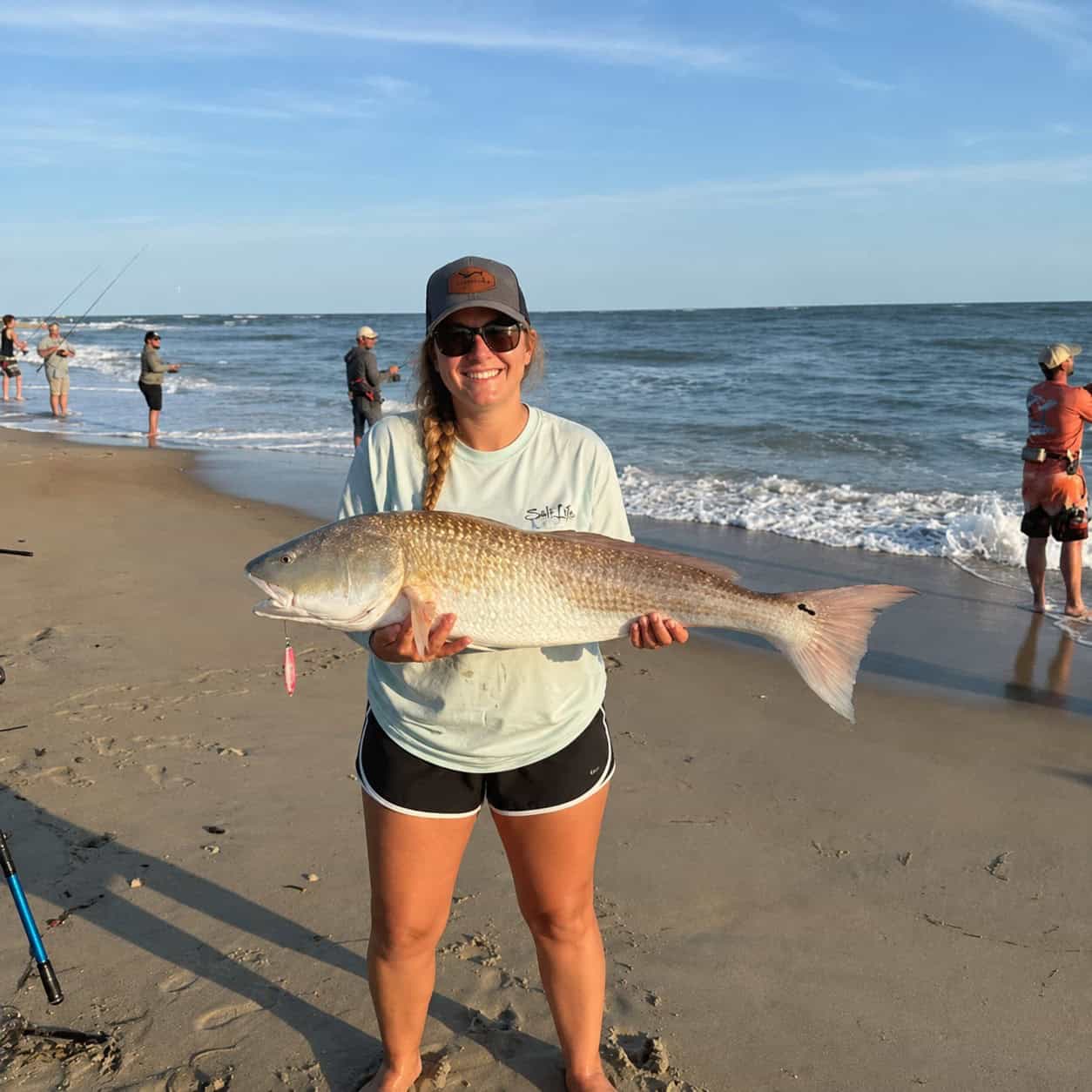 Woman holding a large red drum caught on an Outer Banks beach